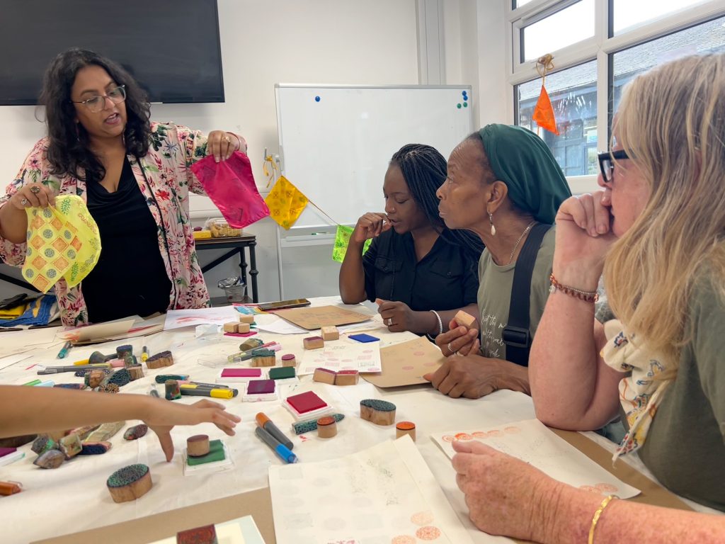 A block printing workshop showing the artist demonstration process while the participants look at her