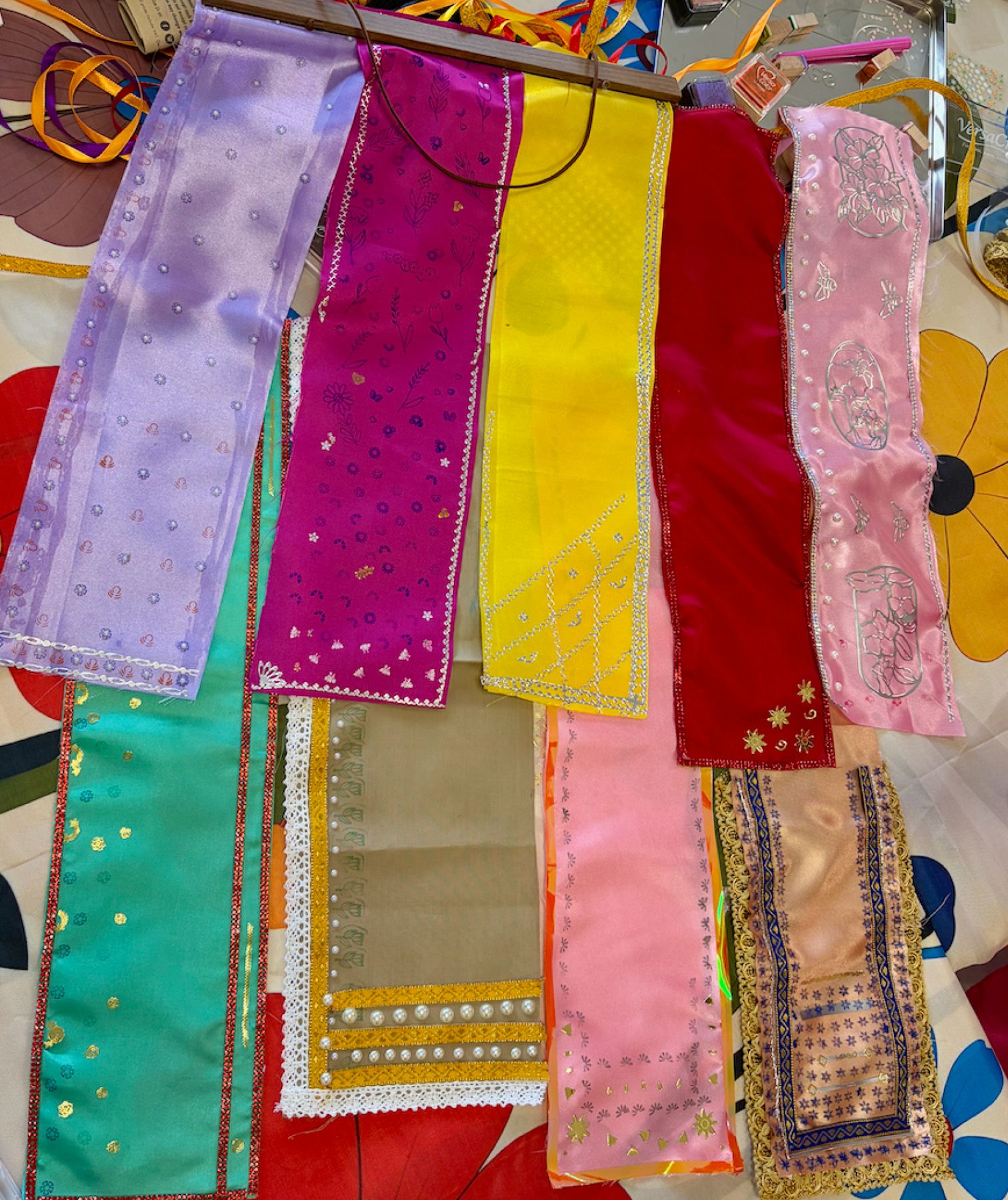 A row of finished mini sarees in different colours, patterns and embellishments, made by workshop participants