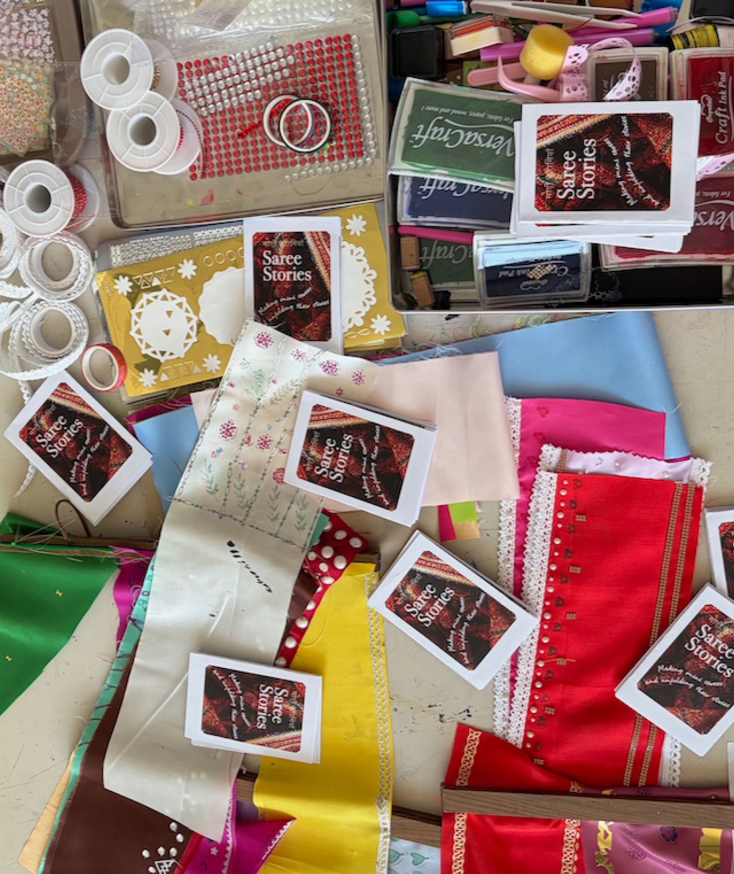 Fabric strips, trims, stamps, ink pads and Saree Stories cards laid out for the mini-saree making activity