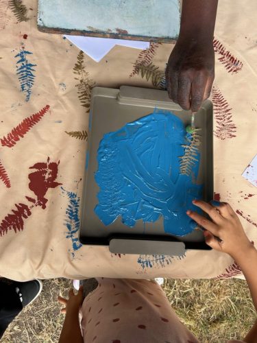 Close-up of a festival printing table with a blue paint tray and fern prints