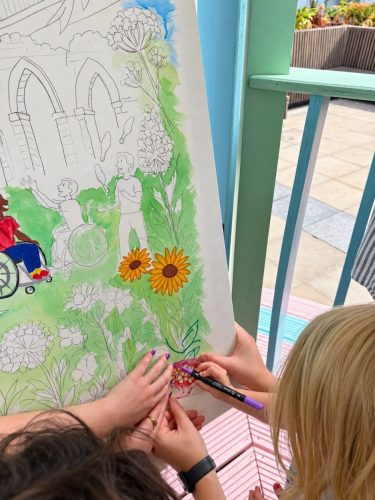 Close-up of hands colouring sunflowers on the Culture Mile canvas