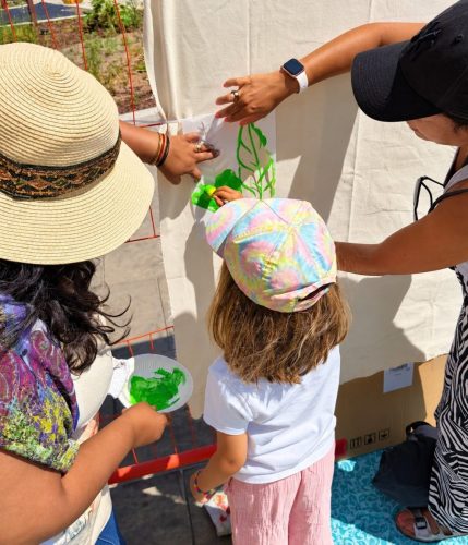 A child in a sun hat painting the East Village canvas with Roopa Basu