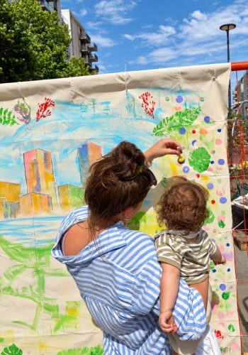 A parent and young child adding colour to the East Village giant canvas